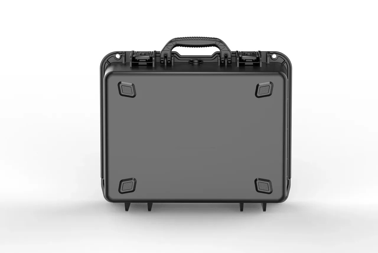Black case closed and standing upright, one square rubber foot at each corner, hinges with round pins on the upper edge, a blank label panel in the middle