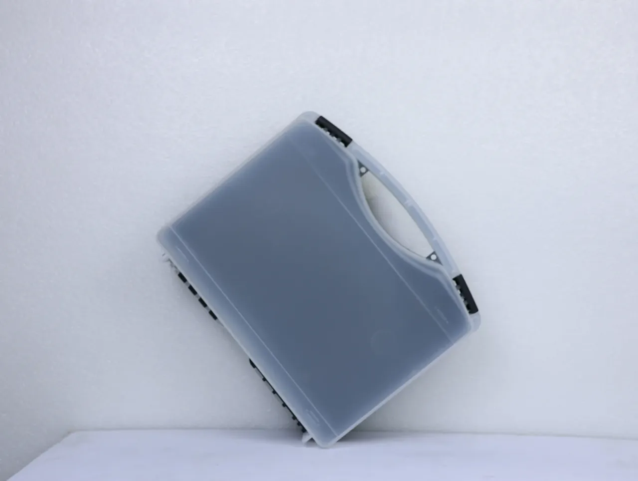 Case Assembly Workstation: a frosted case rests on its side, lid edge forming one white line, black hinge blocks at both ends