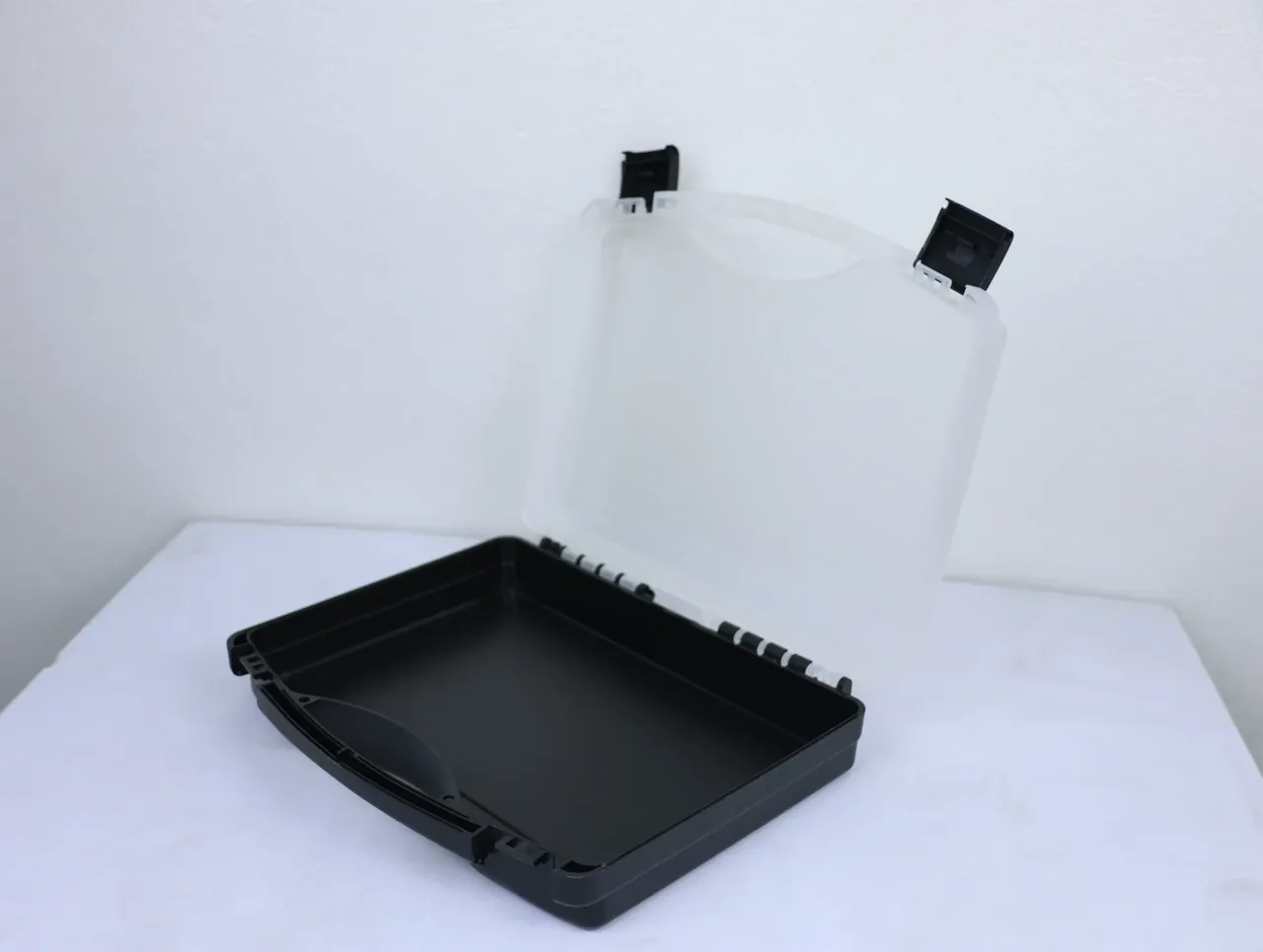 Case Assembly Workstation: black base meeting a frosted lid at a right angle, six white hinge pins at the joint, two black latches
