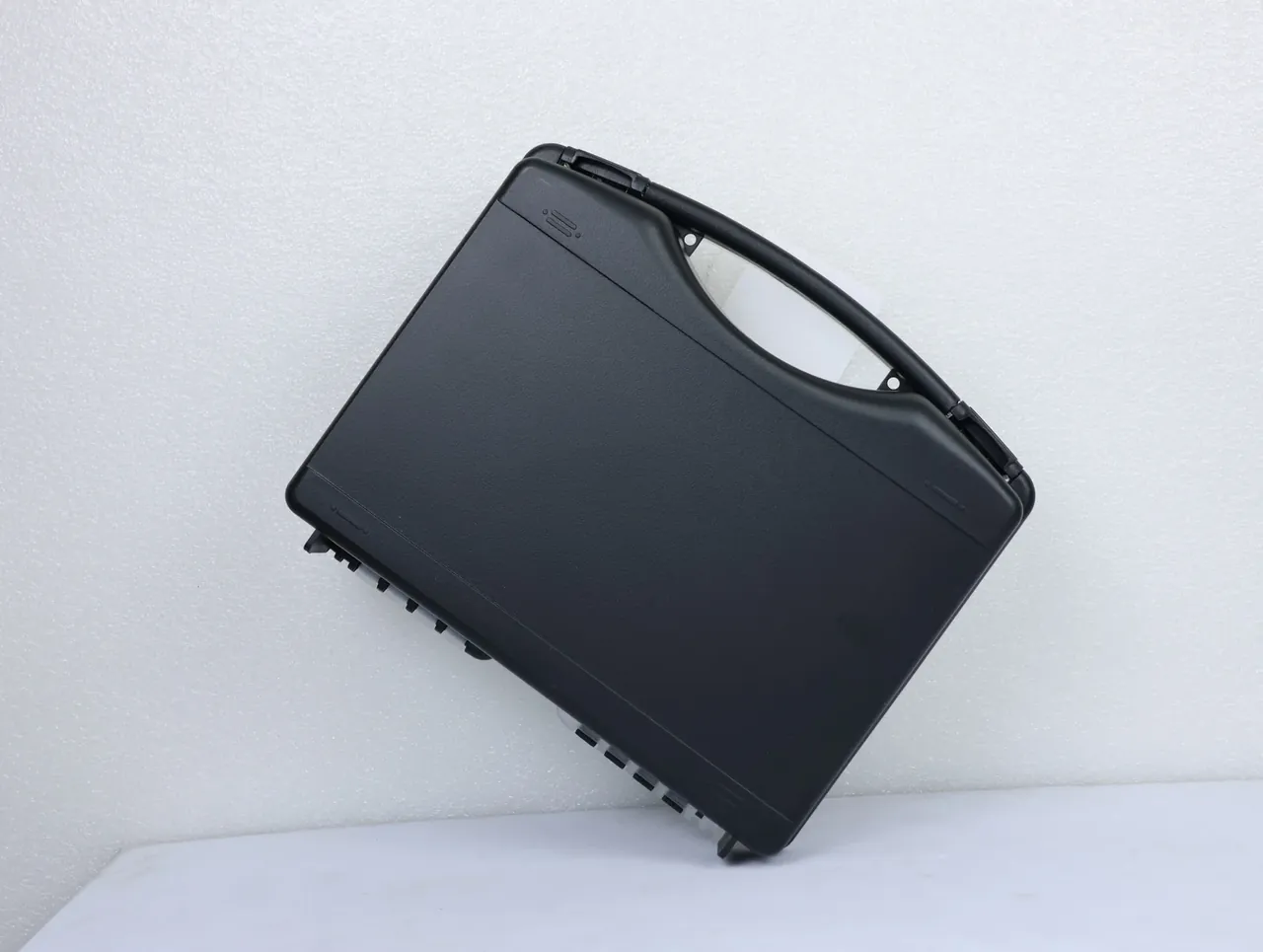 Case Assembly Workstation: a black case stands face-on, flat front panel, hinge blocks at both ends of the top edge, latch teeth lower right