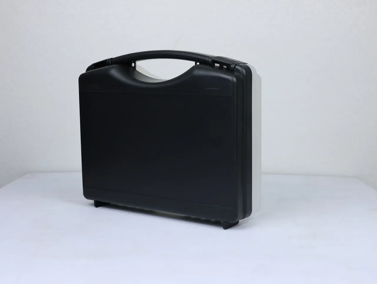 Case Injection Molding Machine output: black and grey case side-on, black front, pale grey back, black hinge pin, vertical parting line
