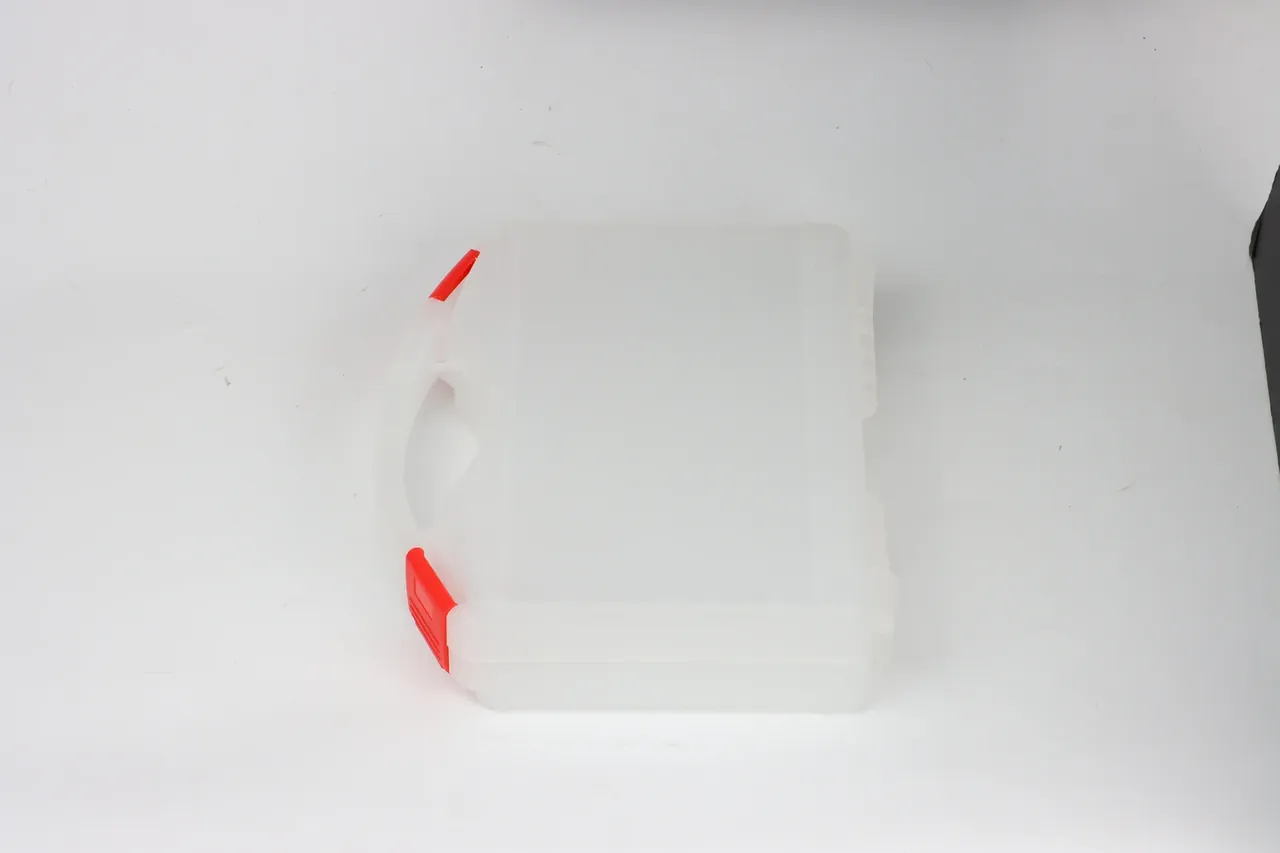 彩色防护箱：同一只乳白箱侧立，左边缘上下各一只橙红锁扣已扣紧，箱底朝右，磨砂表面在顶光下泛出细密纹路