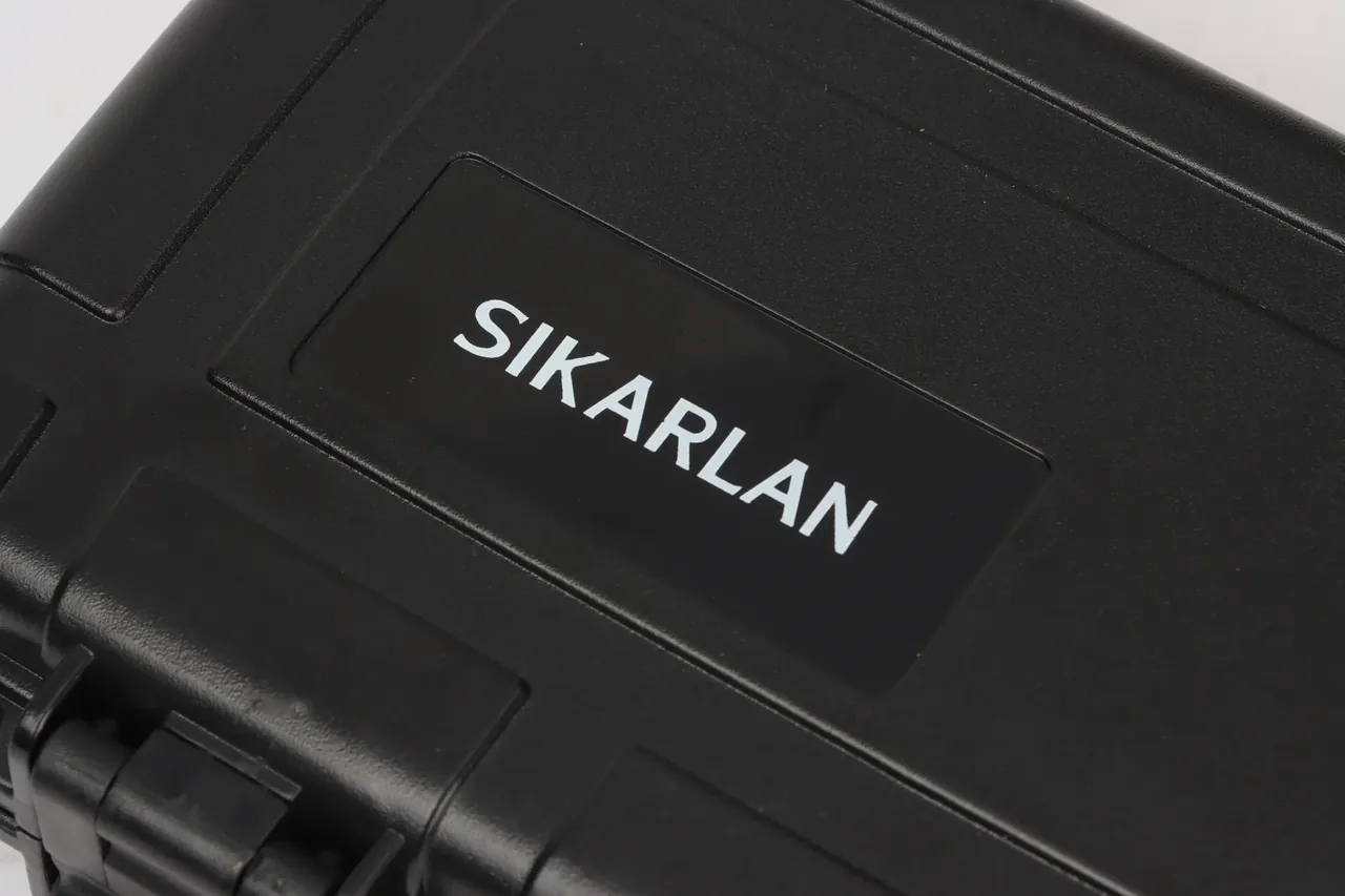 Close-up of the lid label recess with white SIKARLAN lettering on a matte black face inside a raised border
