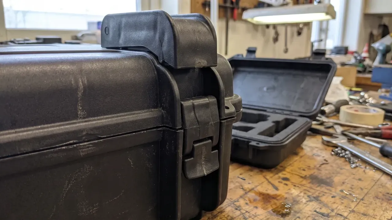 Custom foam insert case: two black cases on a wooden bench, one closed with its latch, one open showing square and bar foam pockets, screws