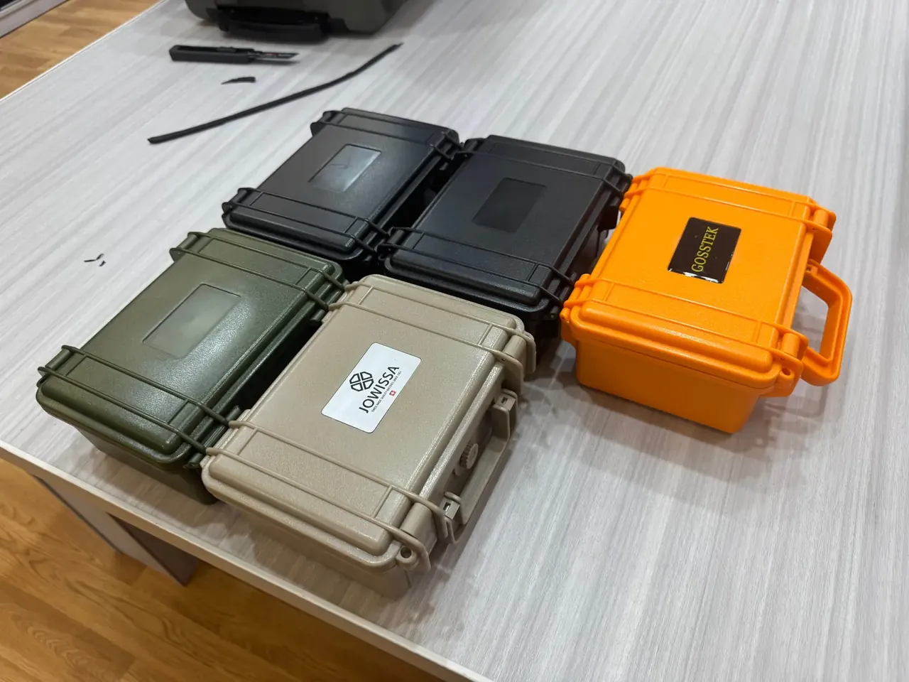 Custom Interior Protective Case: five small closed cases on a wood-grain table, two black, one olive, one tan and one orange