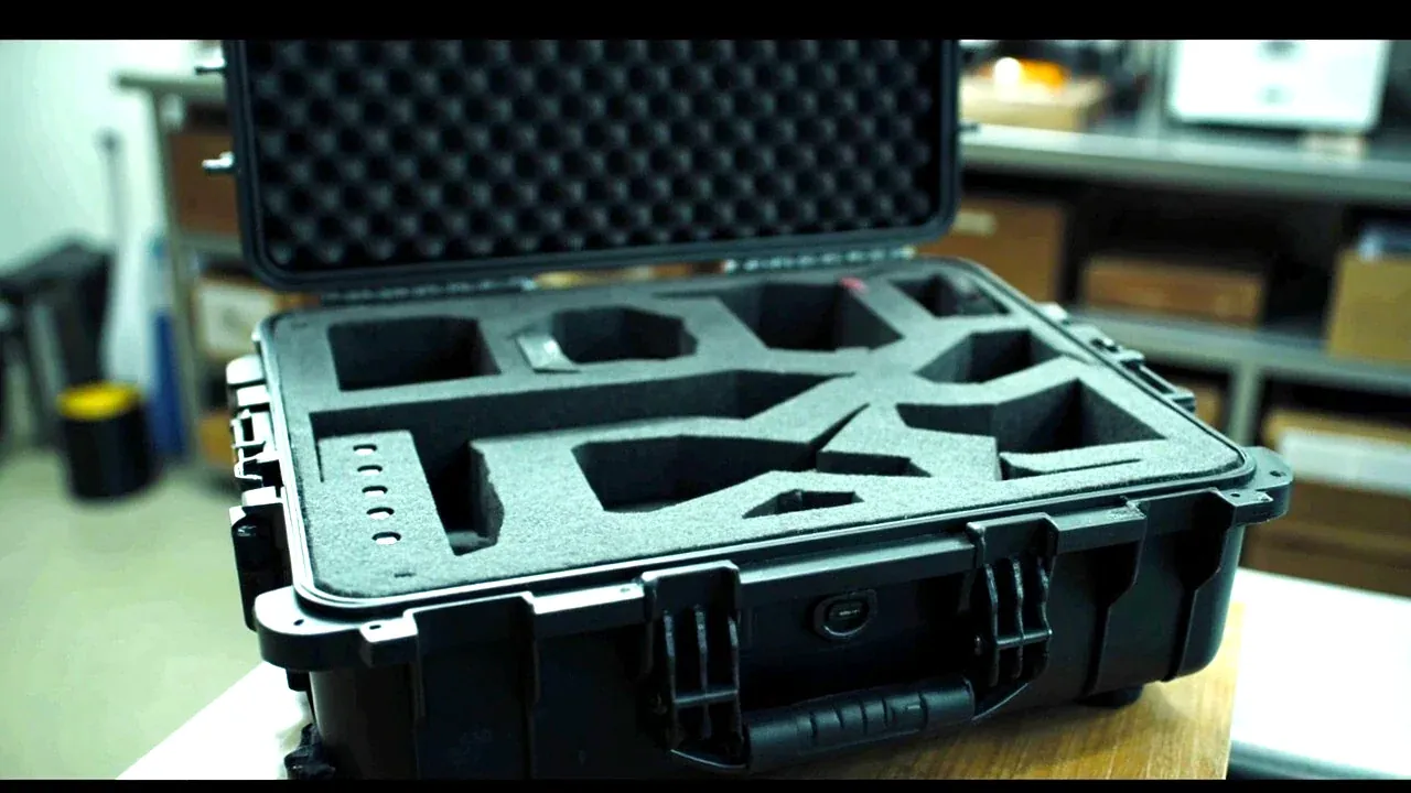 A drone case with a replacement foam insert section and added battery dividers, open on a bench