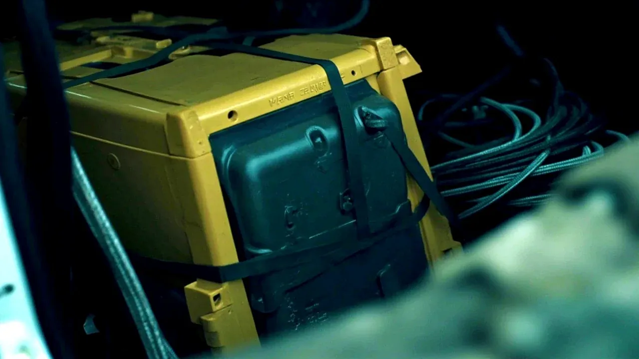 The case strapped in a vehicle cargo area with a coiled cable beside it