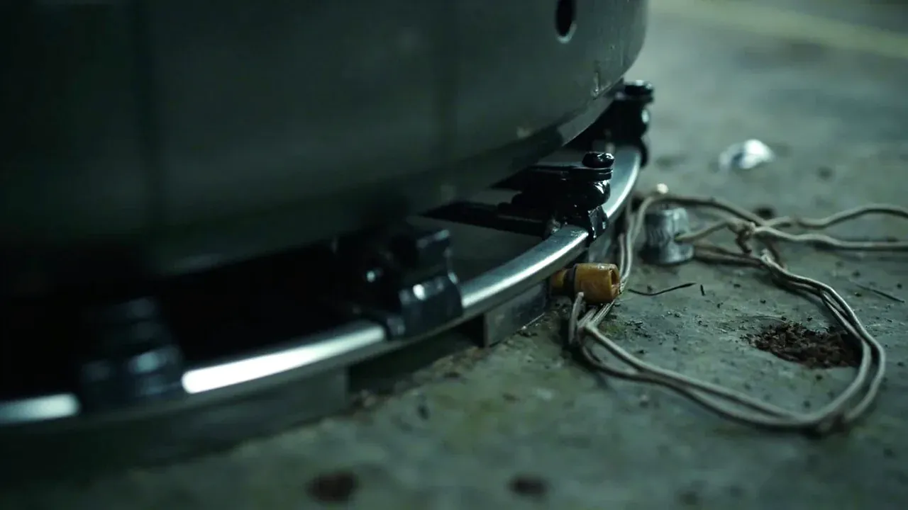 Draw latch clamping the rim beside a ground stud