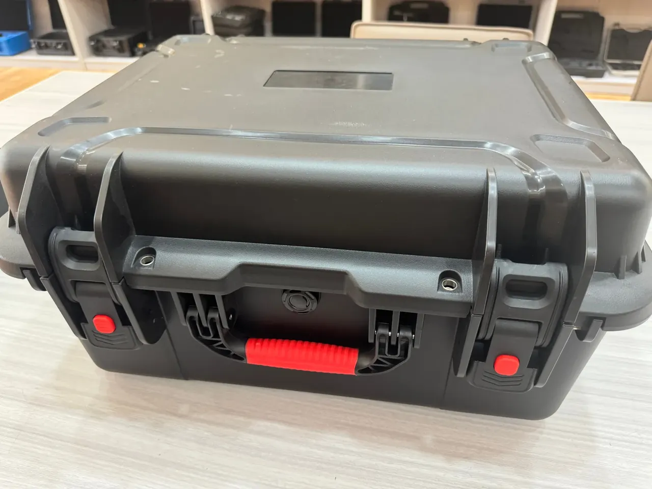 Injection Molded Protective Case: front of a black case with red rubber handle, two latches with red buttons and a round pressure valve