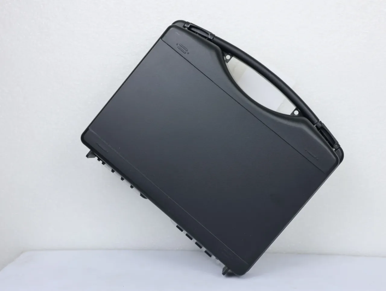 Knife Case: a black case on its side, arched handle moulded into the lid, small rectangular mark upper right, black catches along the lower edge