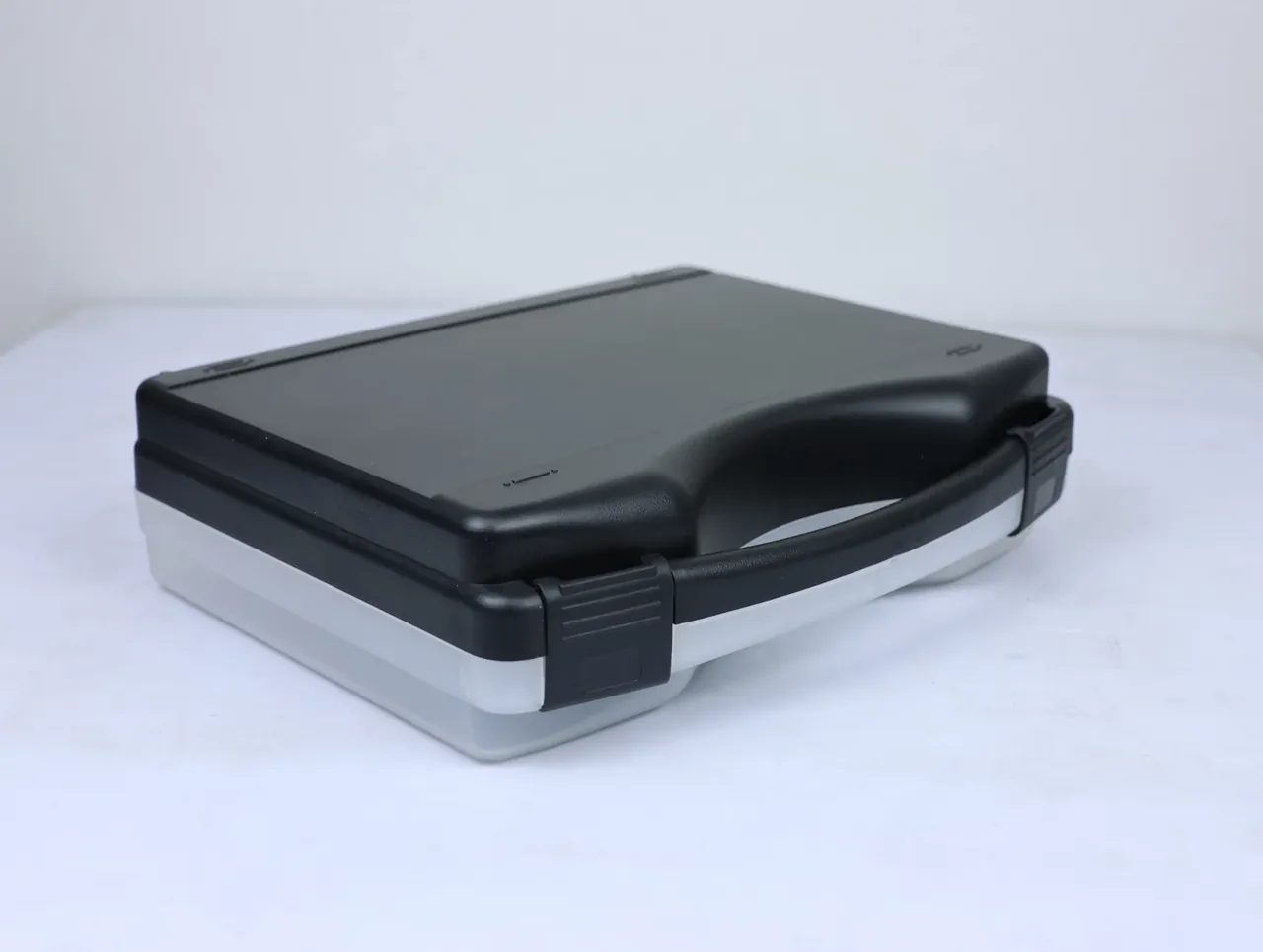 Knife Case: low three-quarter view from the right front, plain black lid, handle recess curving into the side, grey base corner, two latches