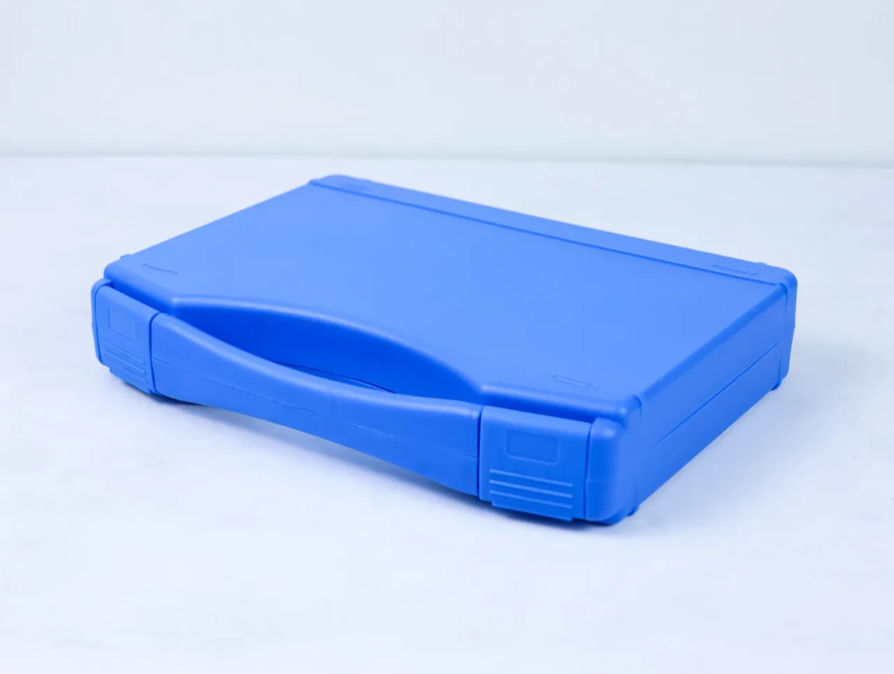 Large Protective Case: the same blue case at an angle on a white floor, narrow side and two long latches visible, a faint shadow beneath