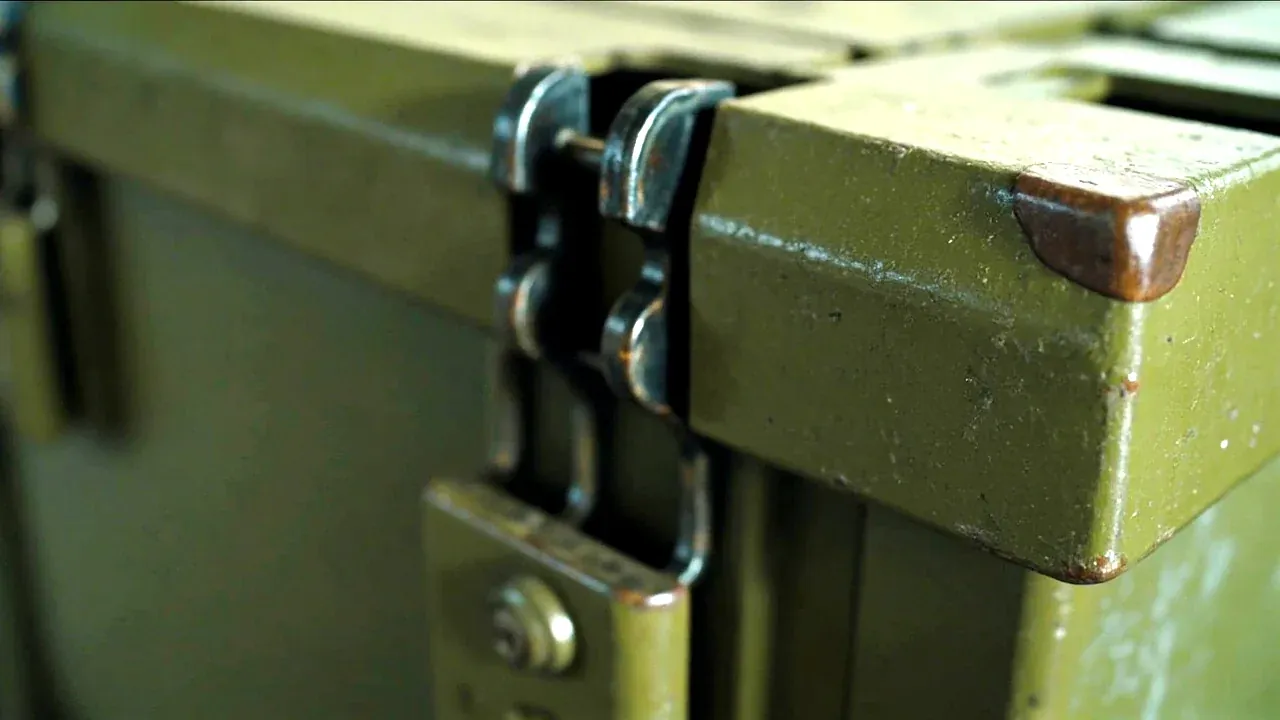 Close-up of a heavy-duty latch pair and a reinforced corner on a logistics box, paint worn at contact patches