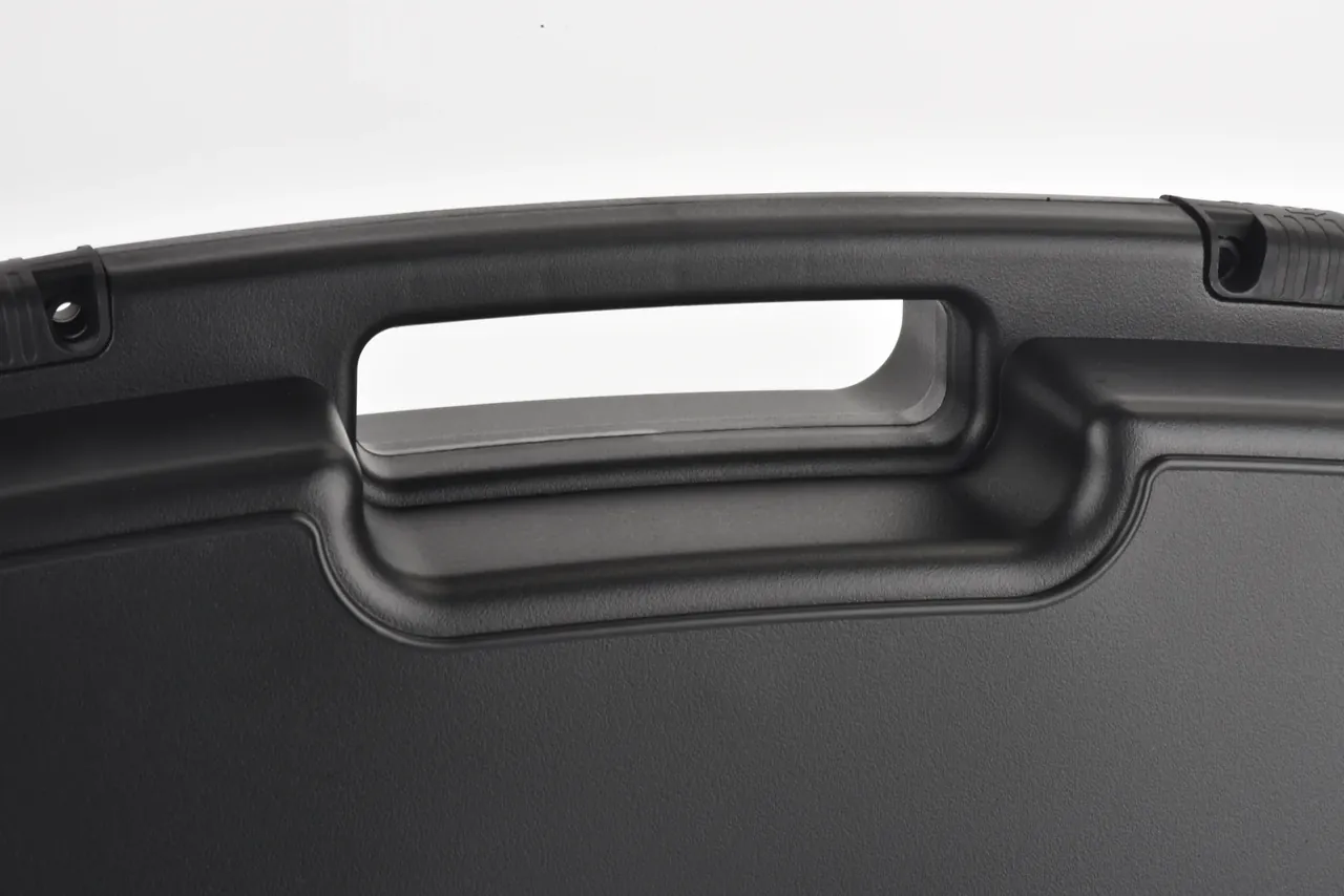 Close view of the moulded handle opening through the lid edge, radiused lower lip, both latch bosses in frame
