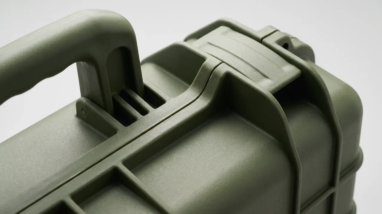 Plastic case with custom foam cutout: olive green shell close-up, folding handle half raised, two ribs beside the handle mount, hinge bosses