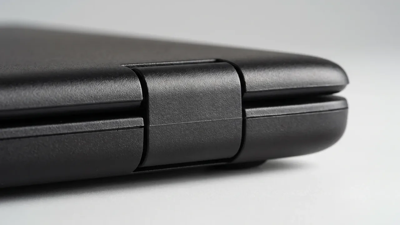 Plastic trolley case manufacturer: close-up of a black case corner, lid seam meeting the base, a moulded bumper over the joint, in side light