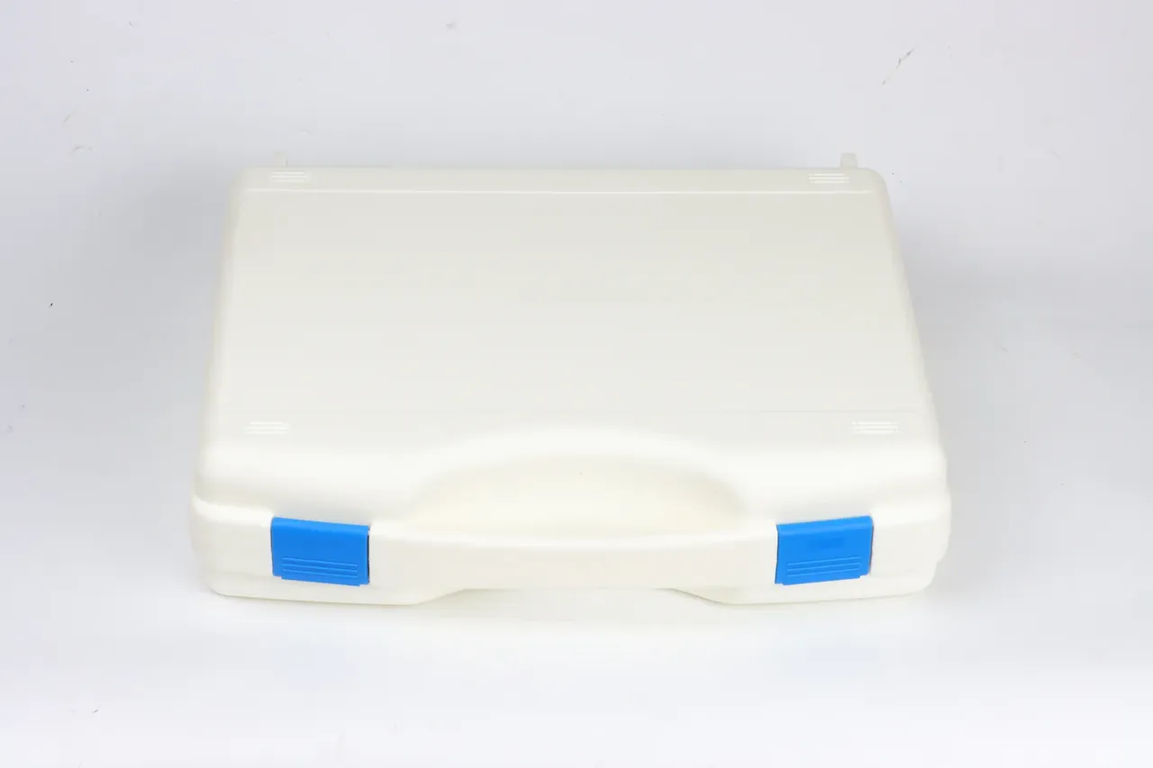 Ivory case from above, two blue latches along the base, handle recess at the front, two small lugs at the top edge