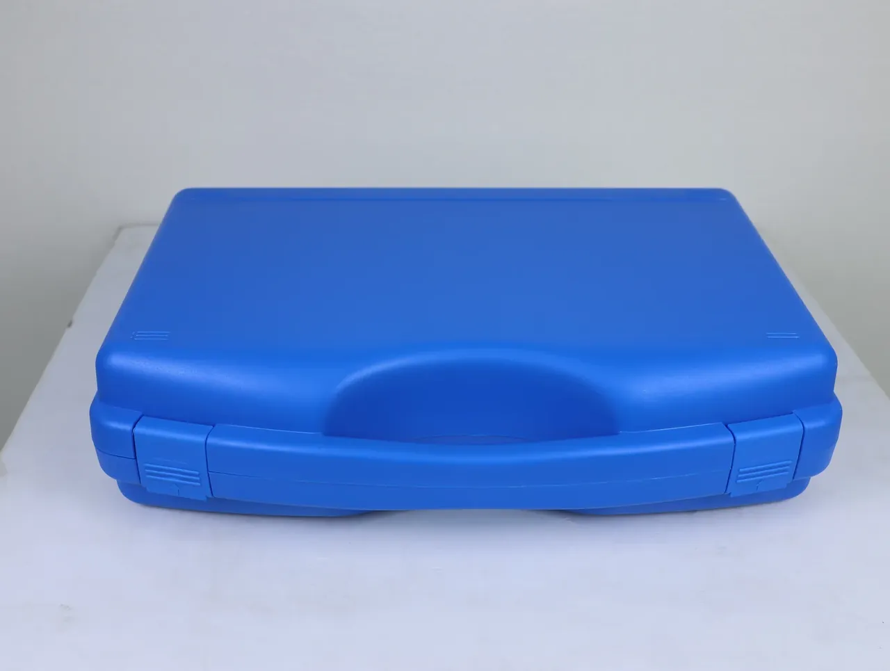A blue case of the same pattern lying closed, lid seam flush and side latches flat against the wall