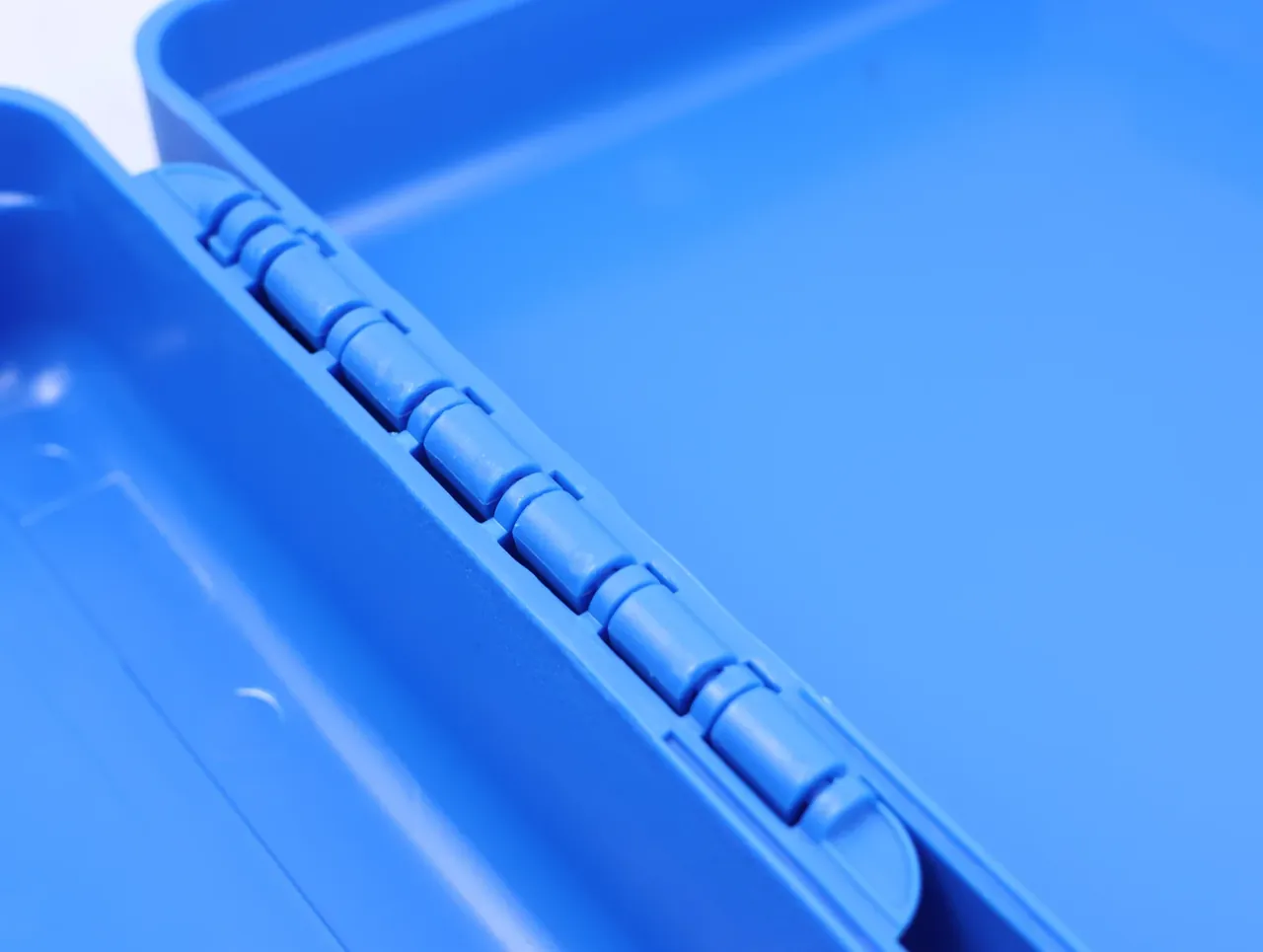 Close-up of the continuous hinge moulded into the rear of a blue case, segments evenly spaced along its length