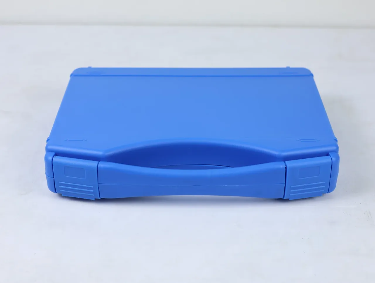 Protective Case Customization Process: blue case flat on a pale floor, lid up, both latches turned outward, handle recess curving