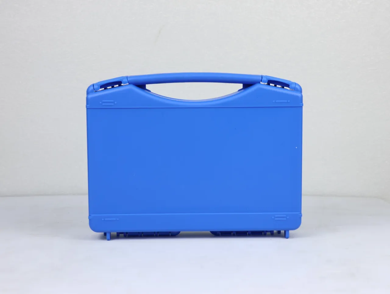 Protective Case Customization Process: closed blue case standing against a pale wall, arched handle and two latches on top, four short feet below