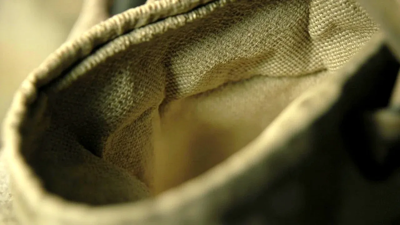 Close-up of the weave and edge binding of a plain canvas tool bag surface