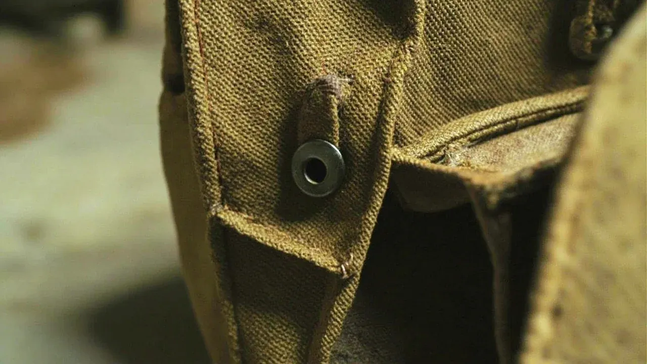Close-up of the reinforced base seam and metal eyelets of a canvas tool bag