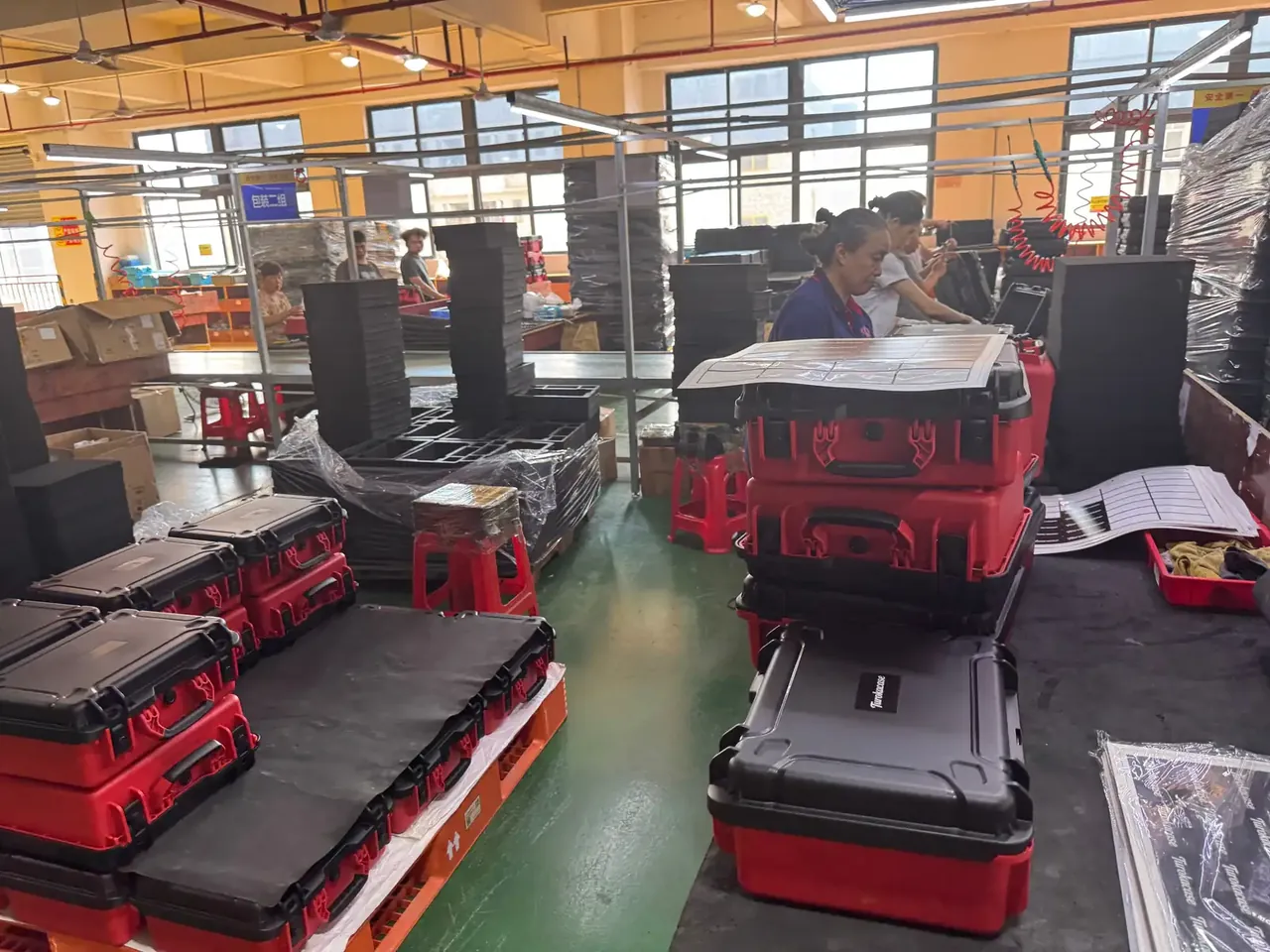 Tool Carrier: red and black cases tiered on a pallet, a worker labelling the top case, racks behind