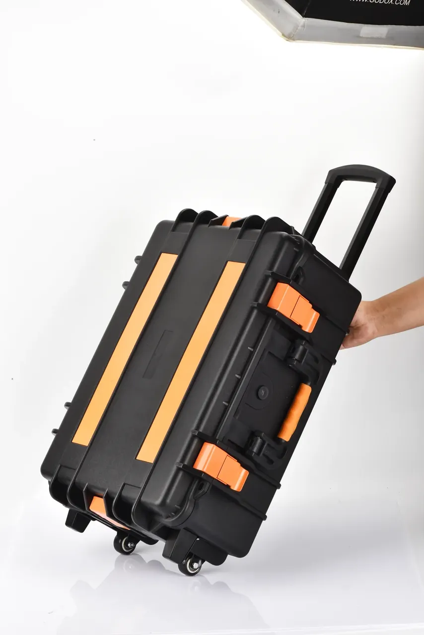 A hand on the side handle of the case, tilted with its wheels on the floor and the handle still extended